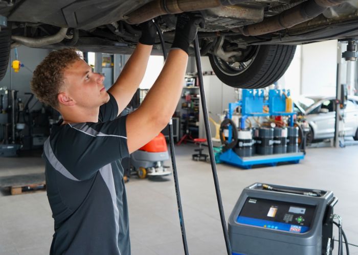 kfz_hildebrand-automatikgetriebe_oelwechsel_mit_spuelung-700x500 Werkstatt Mitarbeiter wechselt Automatik-Getriebeöl an einem Fahrzeug.