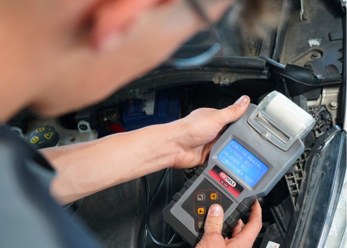 kfz_hildebrand-batteriecheck-700x500 Mitarbeiter führt in der Kfz-Werkstatt einen Batteriecheck durch.
