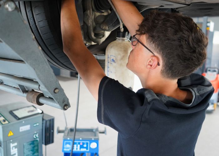 kfz_hildebrand-bremsenservice_und_bremsfluessigkeit-700x500 Werkstatt Mitarbeiter wechselt Bremsenflüssigkeit an einem Fahrzeug.