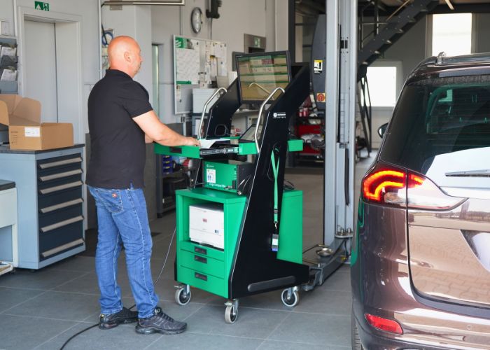 kfz_hildebrand-hu_au-700x500 Werkstatt Mitarbeiter führt Abgasuntersuchung an einem Fahrzeug durch.