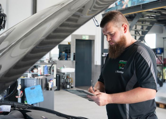 kfz_hildebrand-inspektion_nach_herstellervorgaben-700x500 Mitarbeiter führt in der Kfz-Werkstatt eine Inspektion nach Herstellervorgaben durch.