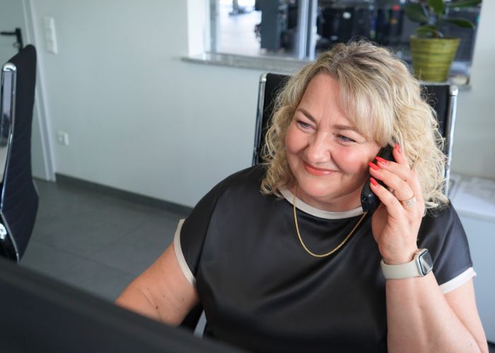 kfz_hildebrand-reifenberatung-700x500 Mitarbeiterin sitzt am Empfang und berät einen Kunden telefonisch.