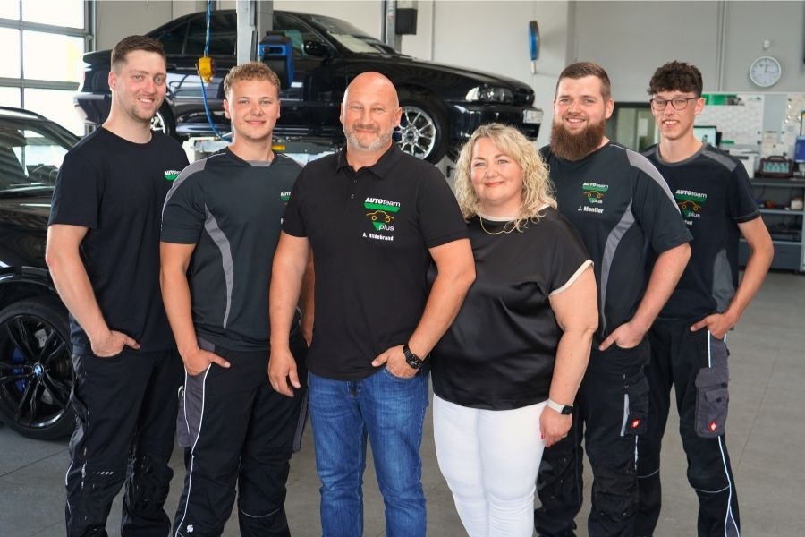 Teamfoto aller Mitarbeiter von Kfz-Meisterbetrieb Hildebrand in der Werkstatt.