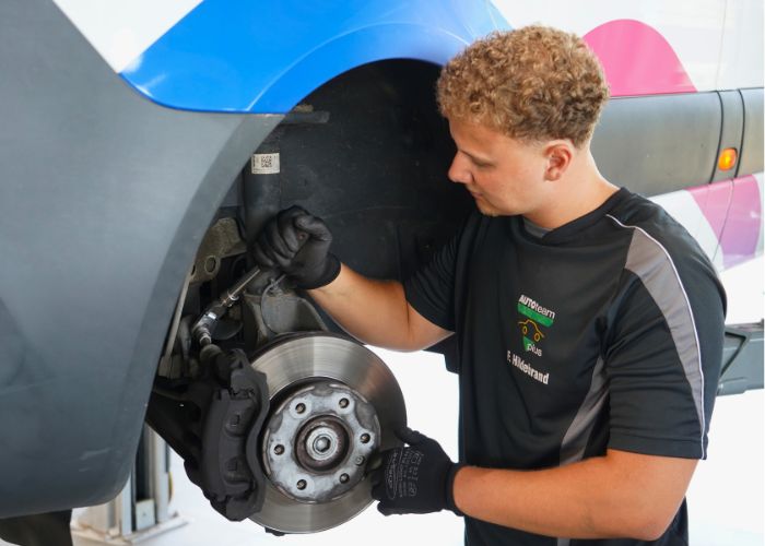 Werkstatt Mitarbeiter repariert Bremse an einem Fahrzeug.